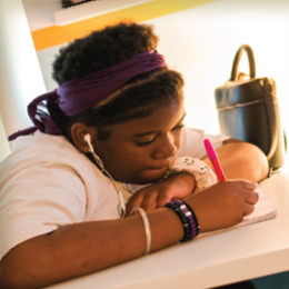 Girl in earbuds writing